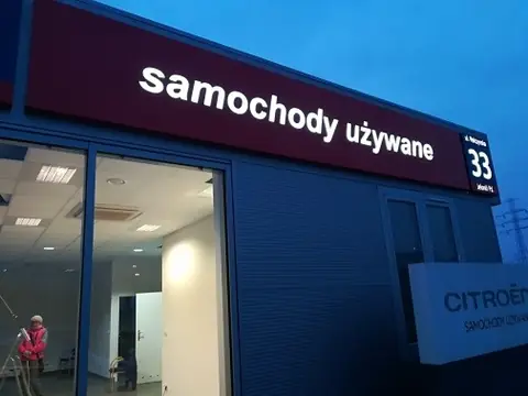 Podświetlany kaseton z napisem samochody używane na budynku salonu