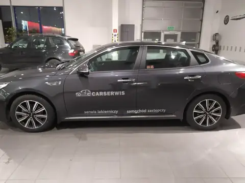 Szary sedan oklejony logo i hasłami serwisu CarSerwis na drzwiach